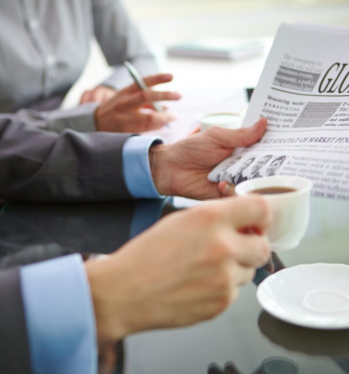 Businessman with newspaper having coffee at workplace